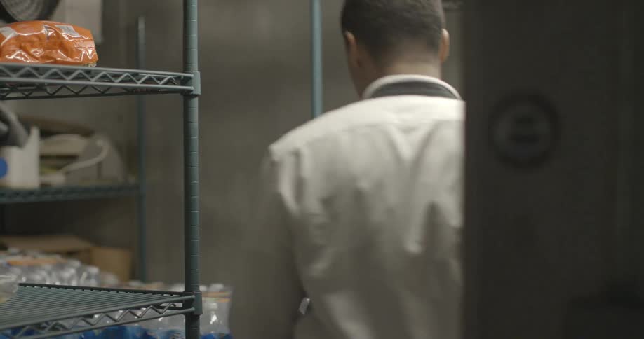 An employee enters a restaurant refrigerator