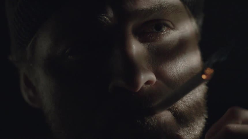 A man smokes a cigarette and exhales smoke
