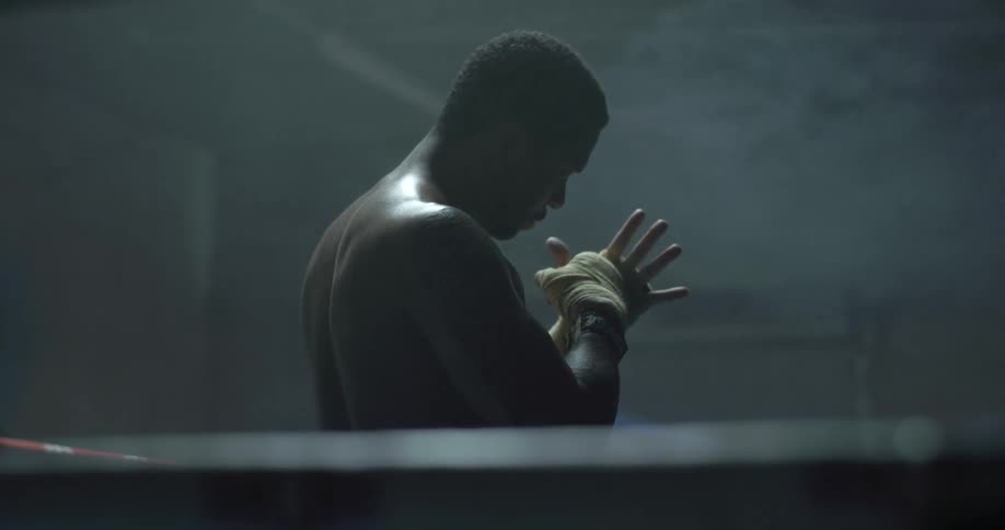 A boxer stands in a boxing ring clenching his hands