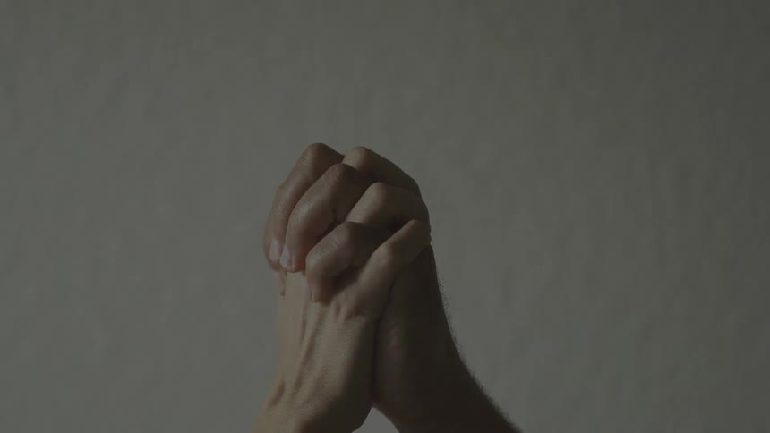 A person clasps their hands together