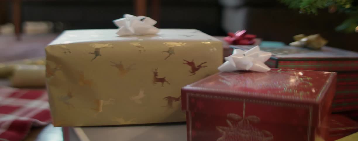 Wrapped christmas gift being placed next to others near the tree