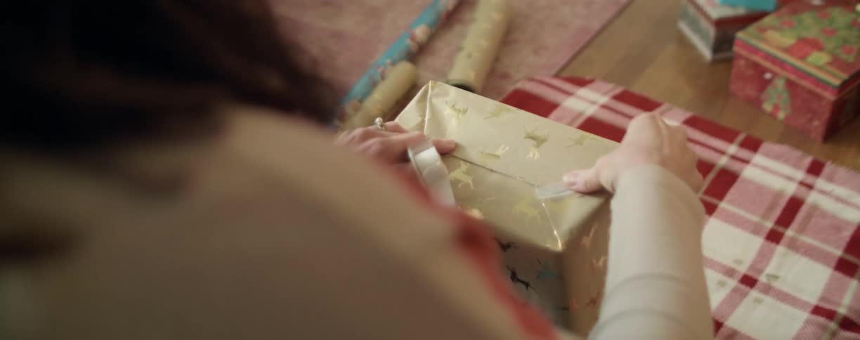 Woman applying tape on a wrapped christmas gift