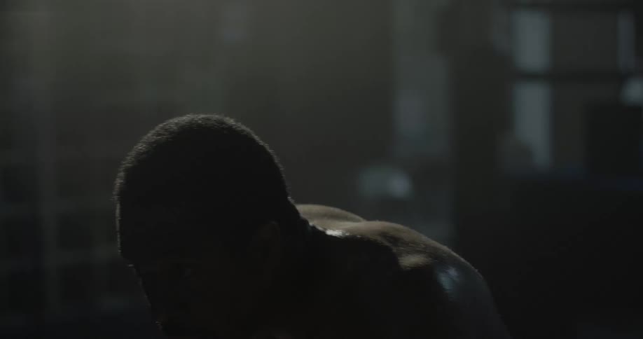 A man is shadow boxing in a dark area