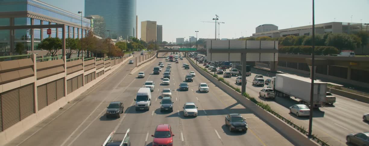 Cars and truck traveling on a multi lane highway in both directions on a bright sunny day