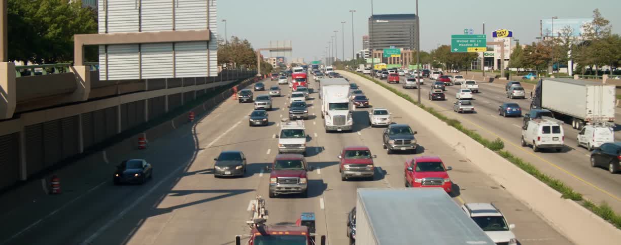 A highway in an urban area filled with trucks and cars