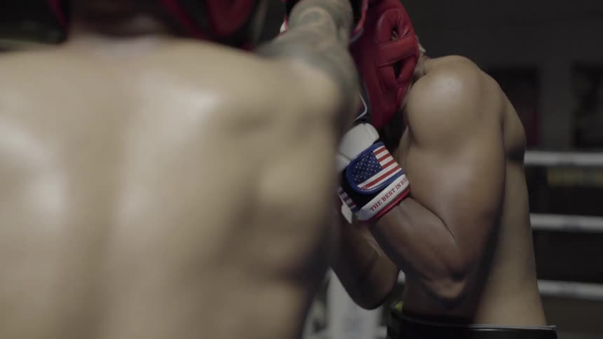 Two boxers train in a ring wearing amateur gear