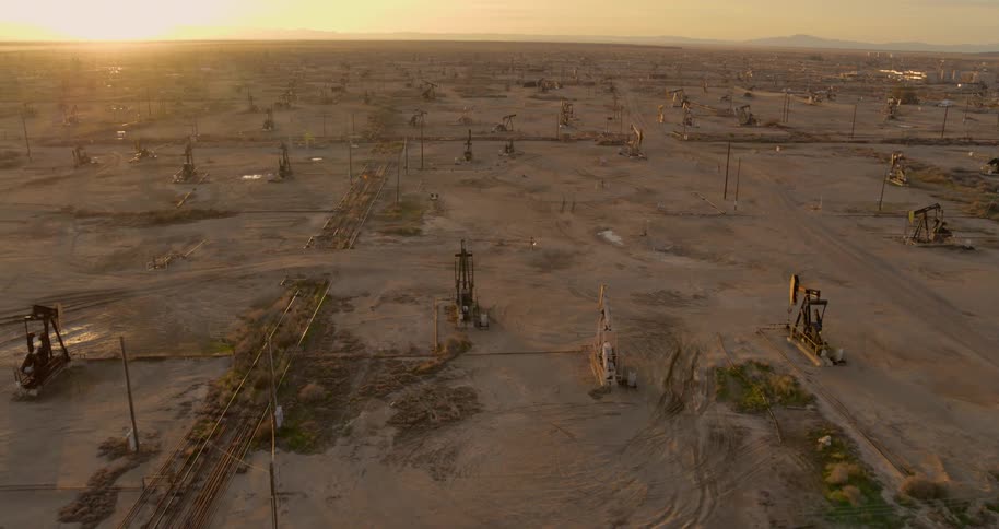 Numerous oil well machinery pumps away on a flat plain