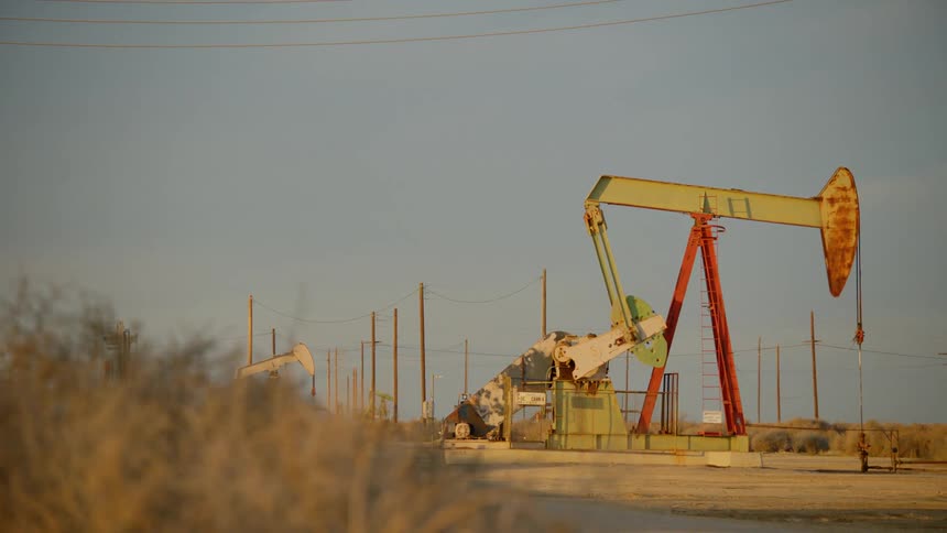 The oil rig is pumping in the distance