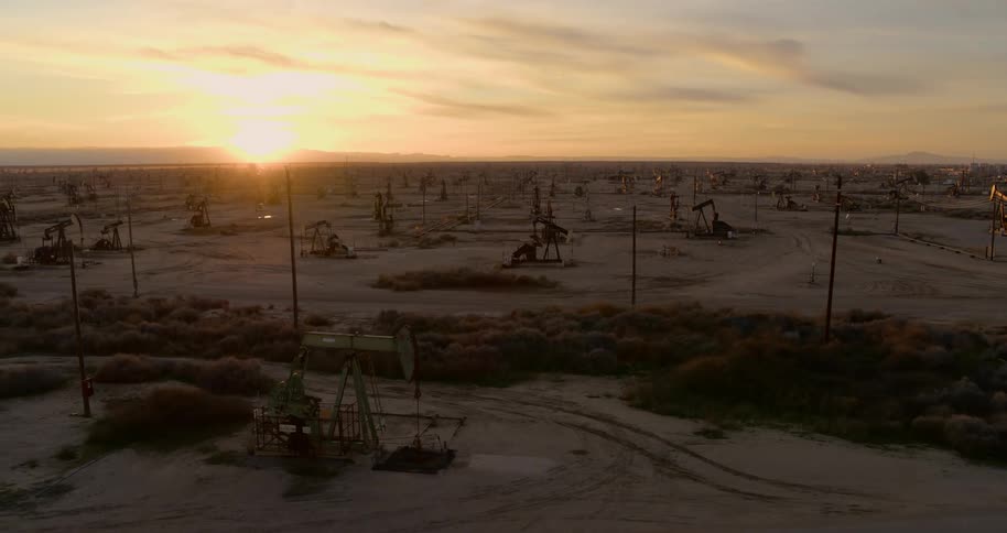 Pumpjacks pump out crude oil in the oil field at dusk