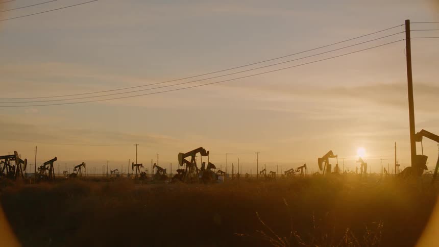 Pumpjacks pump out crude oil in the oil field at sunset