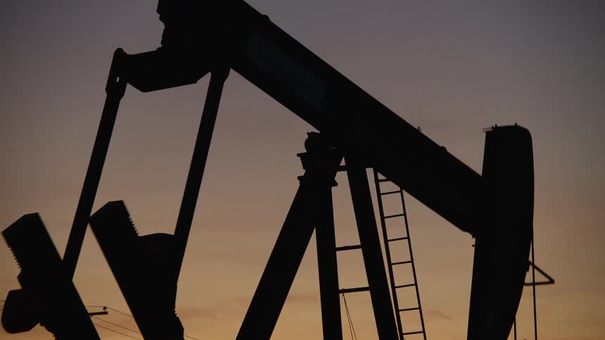 Silhouette of a pumpjack drilling oil at dusk