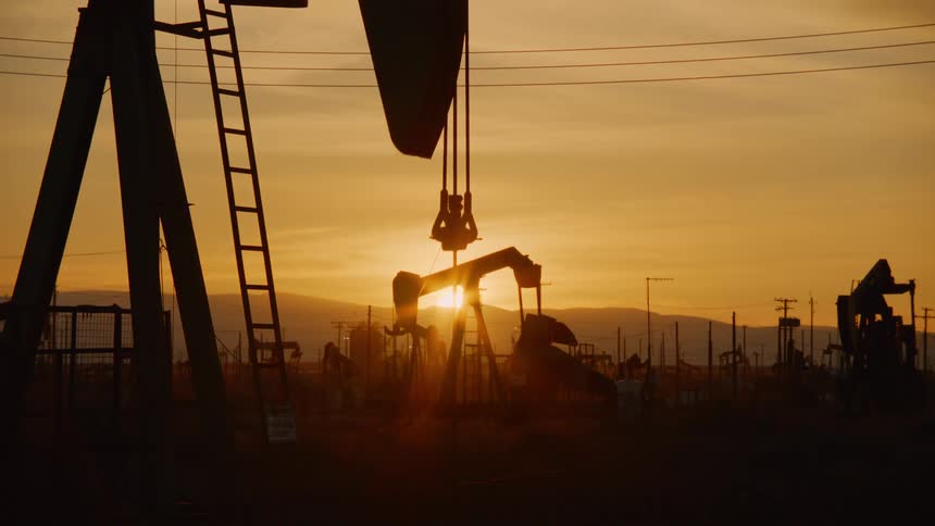 The arms of oil pumps bobbing up and down under a low sun