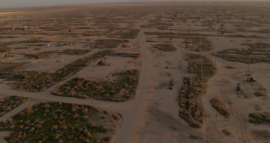 An aerial view of a large oil field with oil pumps at dusk