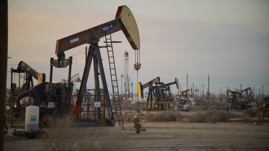 Pumpjacks pump out crude oil in the oilfield at dusk