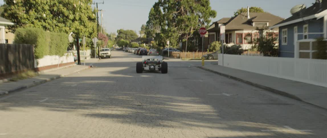 Low slung go cart drives through neighborhood turning at corner