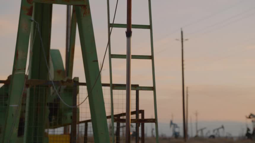 Pumpjacks pump out crude oil in the oil field at dusk