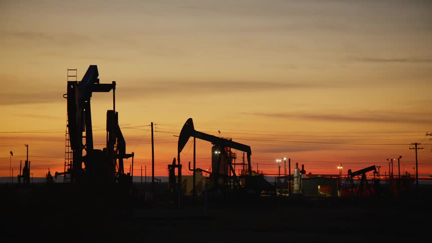 Silhouettes of pumpjacks drilling on an oil field at sunrise