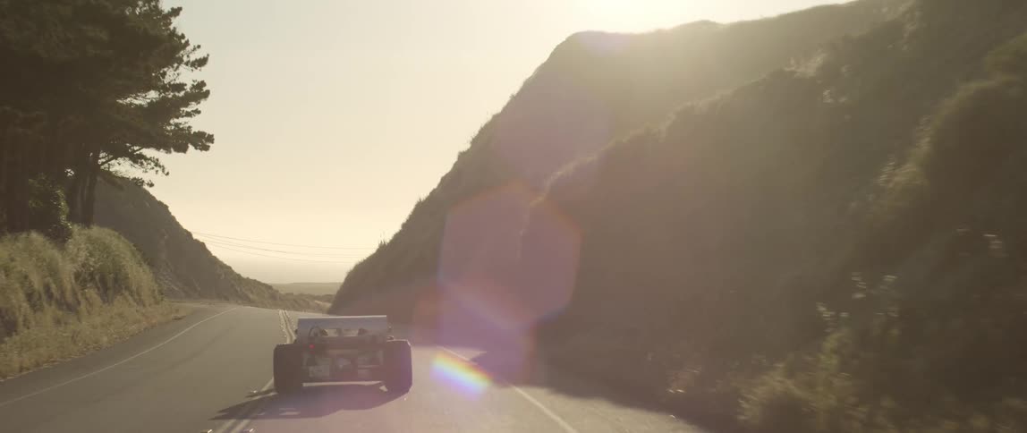 A sports car drives down a curvy mountain side road