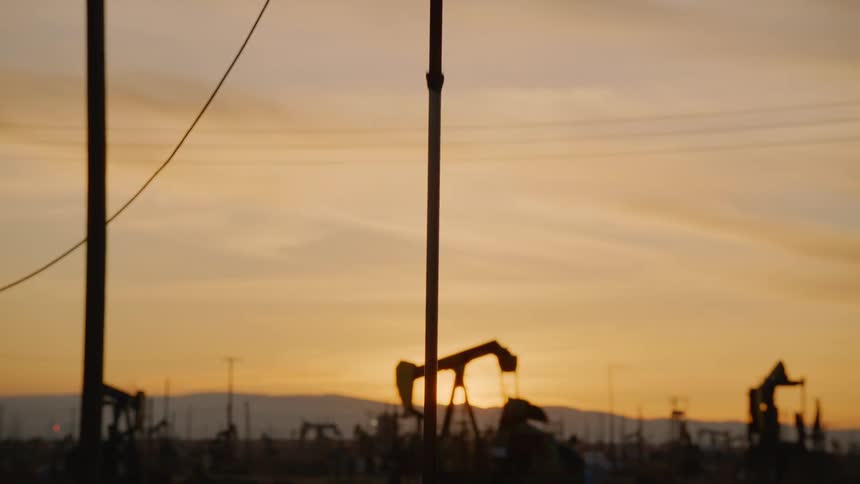Pumpjack pumps out crude oil in the oilfield at dusk