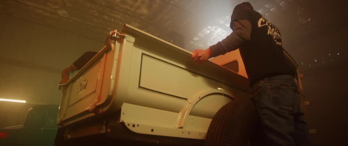 Two mechanics work on a truck in a garage