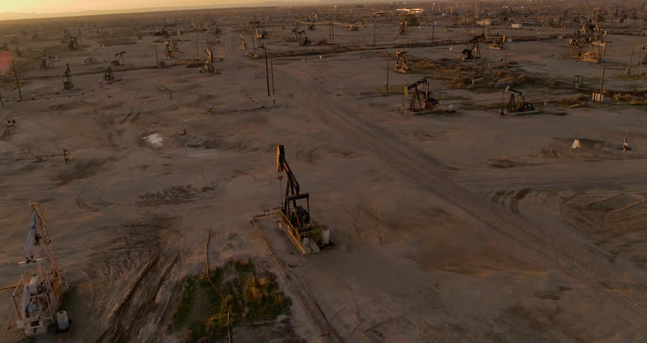 Aerial of pumpjacks drilling on an oilfield at dusk