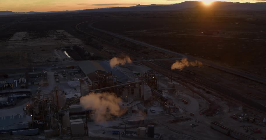 A refinery with smoke emerging from smokestacks in a rural area