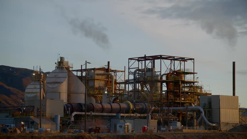 The power plant is giving off smoke from the chimney
