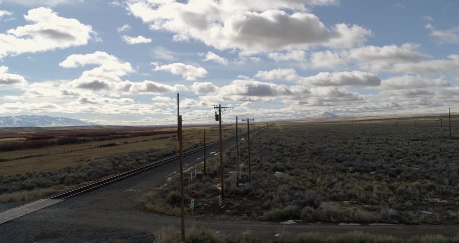 The intersection of a road and a train track running through a vast countryside