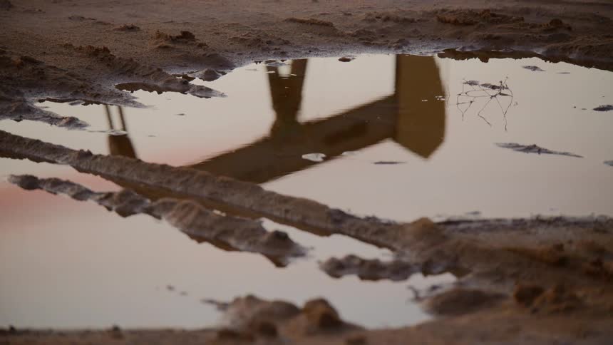 A reflection of a pump jack in a puddle
