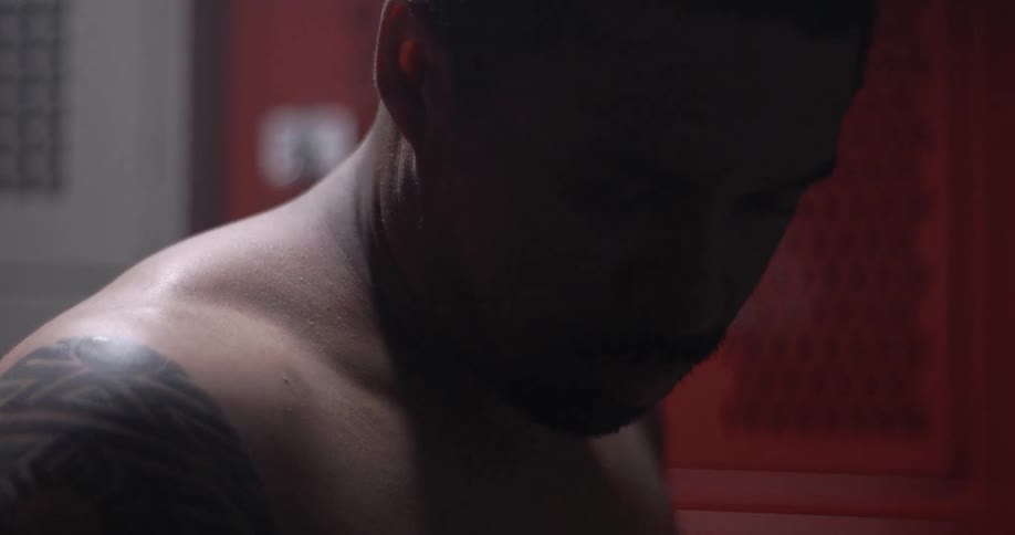 A man removing his shirt in a locker room