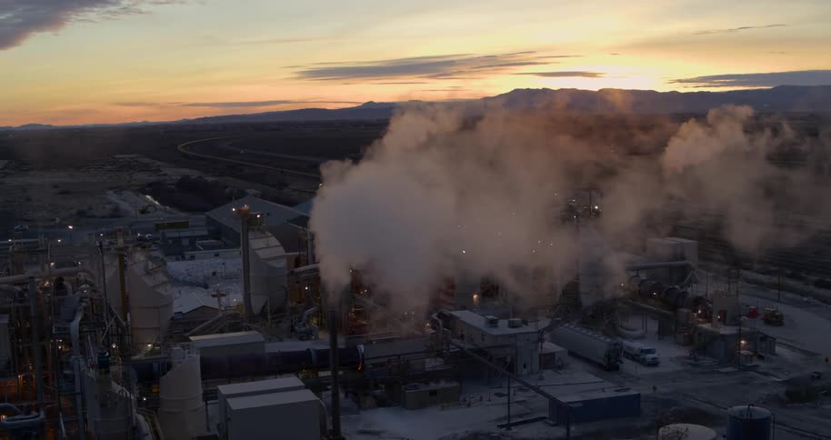 Smoke pours out of smokestacks at a rural plant