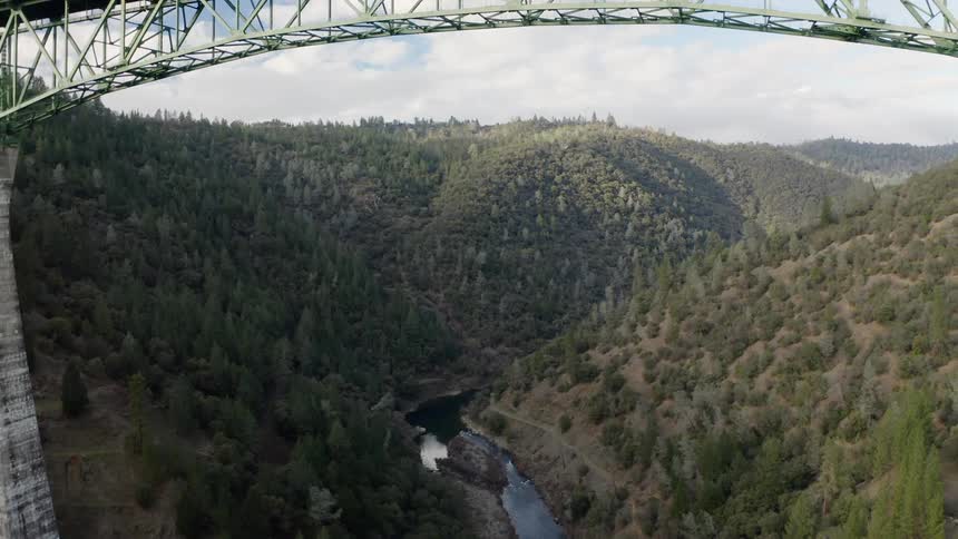 A bridge with a river and a canyon in the background