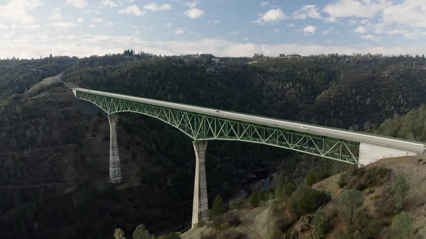 Several cars drive across a bridge over a deep gorge