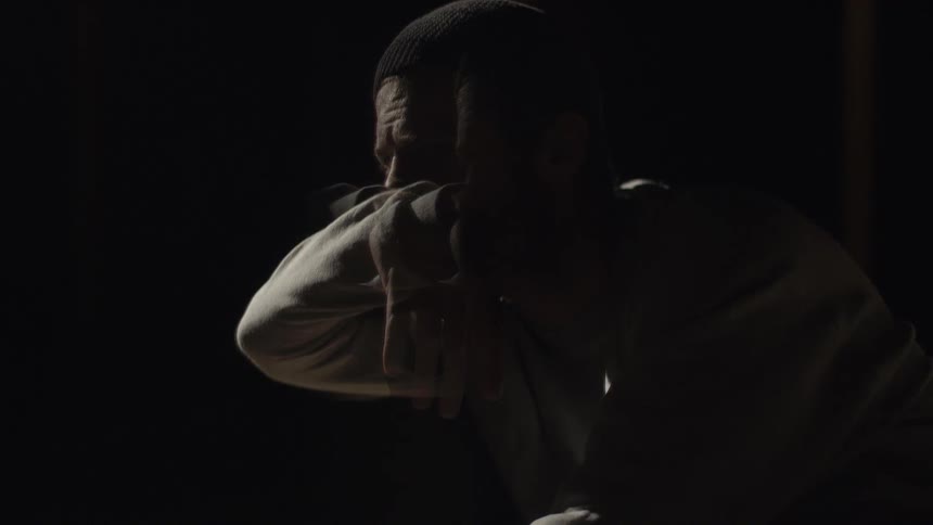 A distraught man sits in a dark room