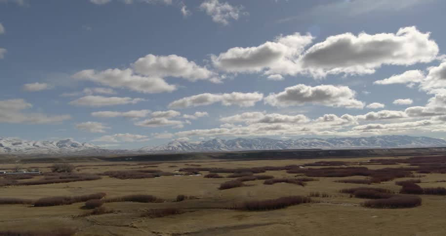 A grassy plain with mountains and the sky in the background