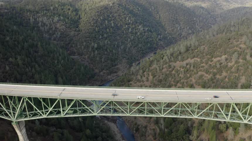 An aerial view of large bridge spanning a valley as cars travel across the divide