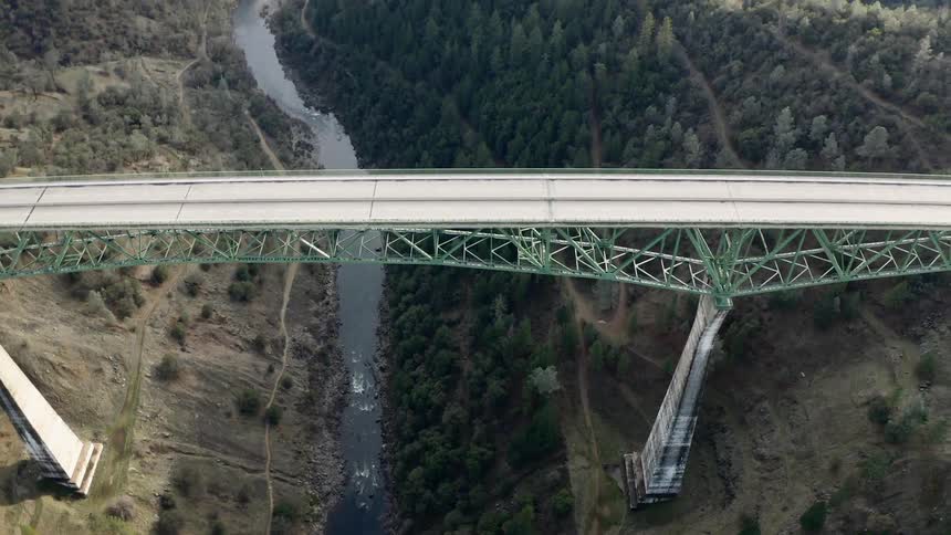 Aerial view of a bridge over a river and a car crossing from one side to the other