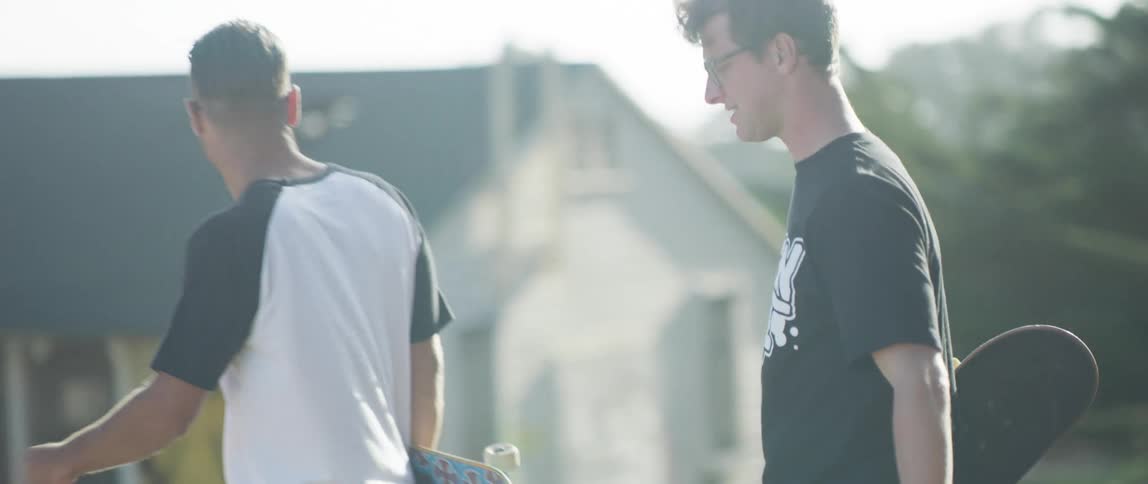 Two men are carrying skate boards outdoors