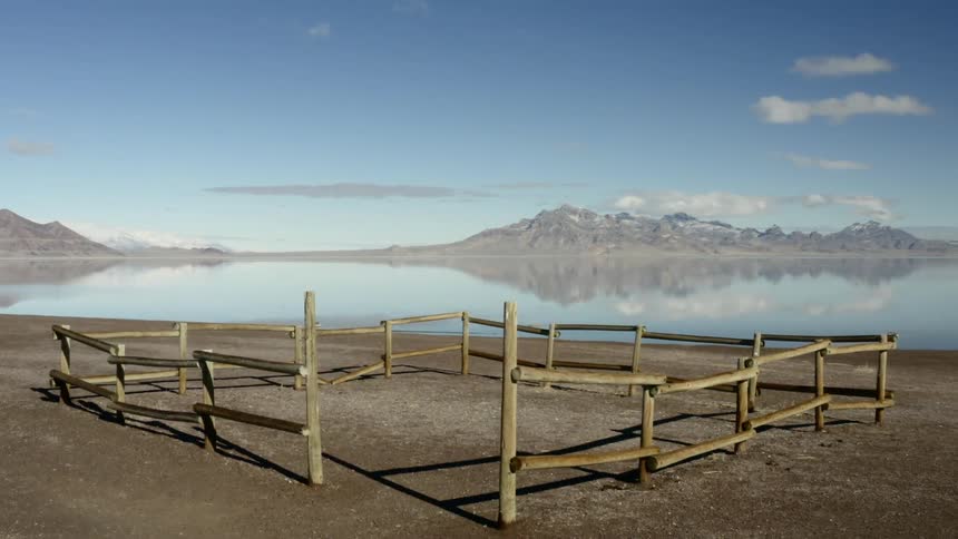 A wooden animal enclosure sits on a the shore of a lake
