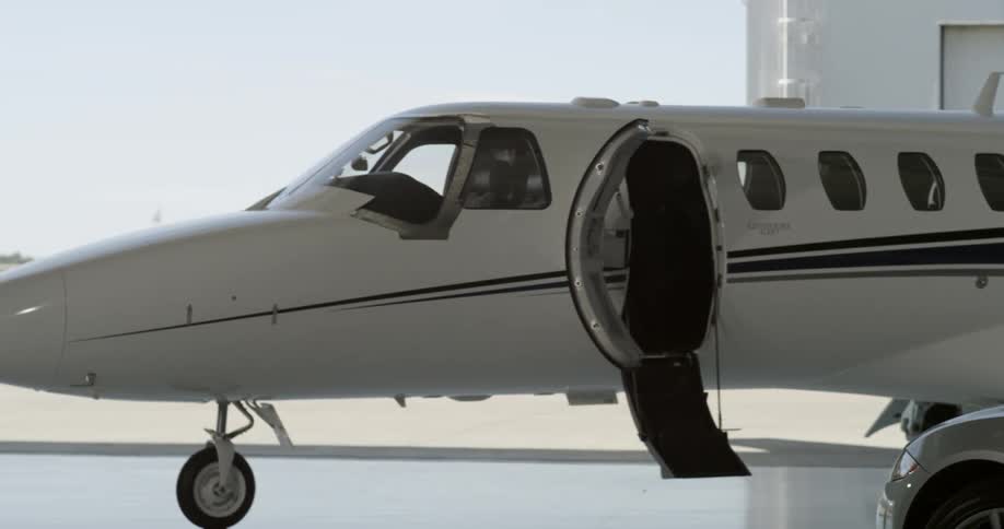 Male and female walk up the steps on to a private jet that inside the hanger