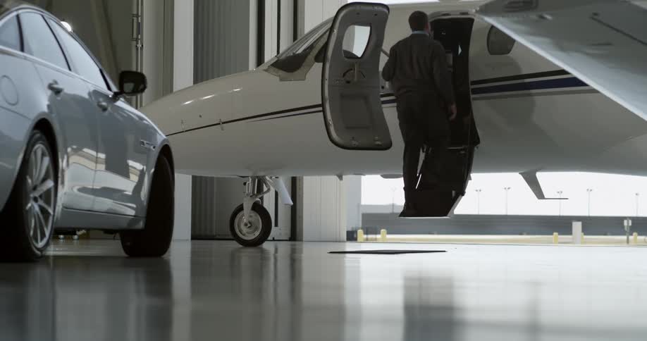 A man and woman climbing a retractable staircase to enter a private jet