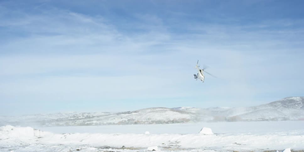 A helicopter flies over a snowy landscape