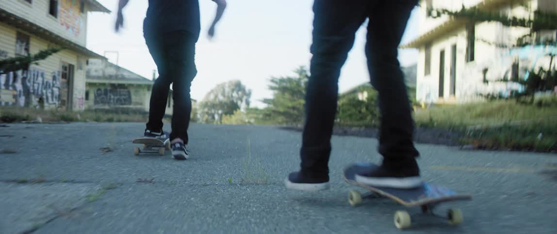 Two people ride skateboards up the street