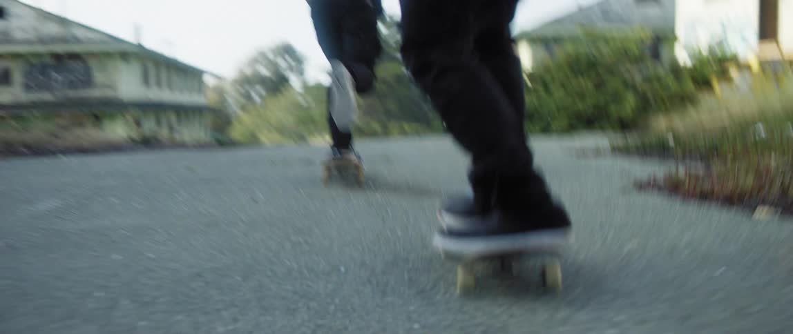 Two boys on skateboards skating on a road in an abandoned neighborhood