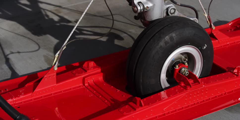 A tire to an aircraft sits in a red locking device