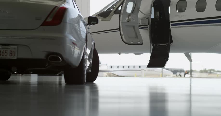 A car sits near a jet plane with an open door