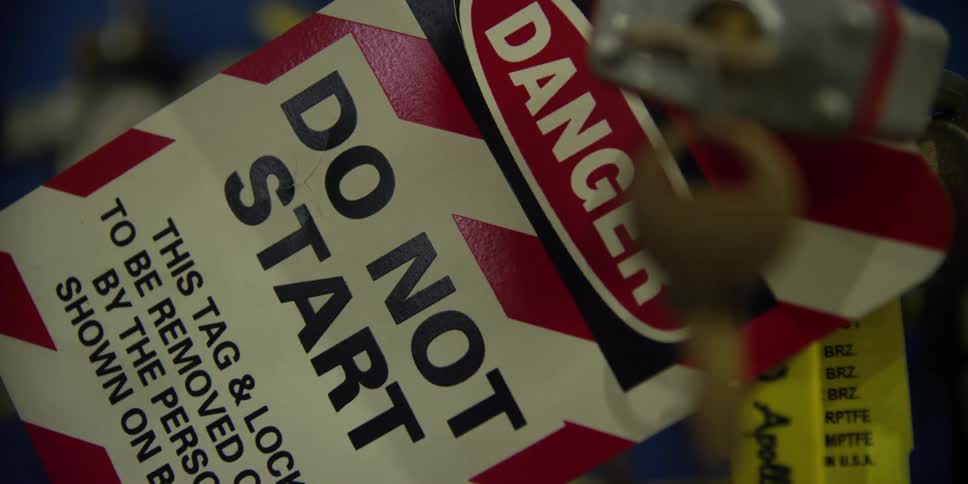 A key hangs and jiggles in front of a warning sign