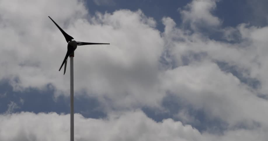 A wind turbine slowly spins in the sky