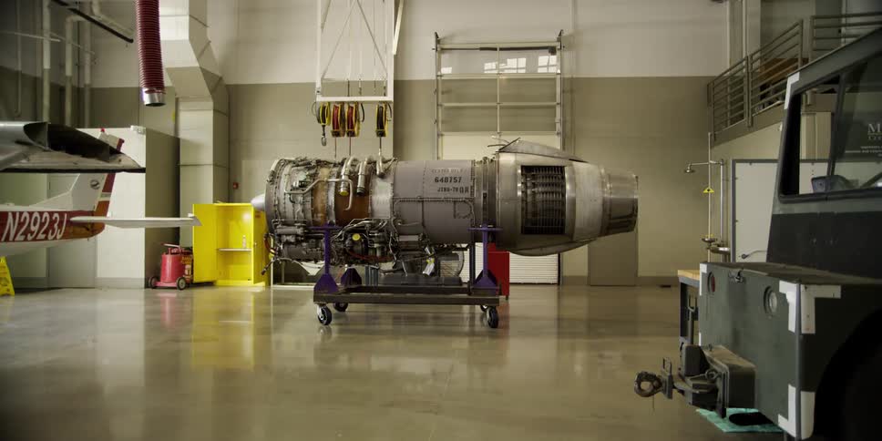 A hanger with an airplane engine next to an airplane