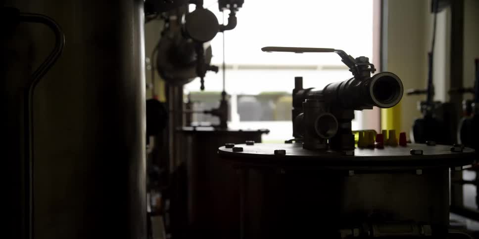 A tank with an attachment for a hose sits in a factory